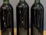 three bottles of wine are lined up on a wooden table
