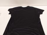 a black shirt sitting on top of a white table next to a pair of scissors