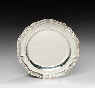 une assiette en argent aux bords festonnés sur un fond blanc