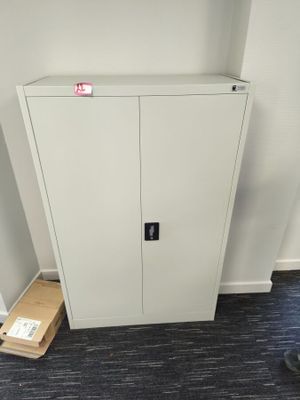 a white cabinet in the corner of a room next to a black chair