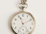 une vieille montre de poche avec une chaîne, posée sur une surface blanche