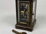 a small clock and a key on a white surface