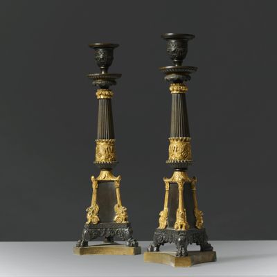 two black and gold candles are sitting on a white table