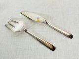 two forks and a knife on a table with a white cloth
