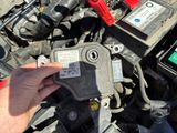 a man that is holding a battery in front of a car