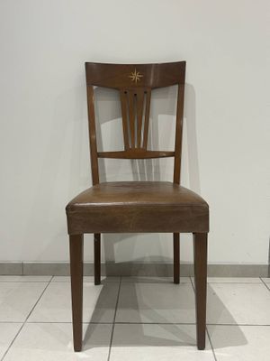 a wooden chair with a leather seat on a tile floor