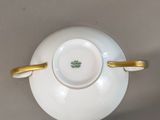 a white cup and saucer with a gold handle on a table