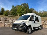 the white van is parked in front of a stone wall