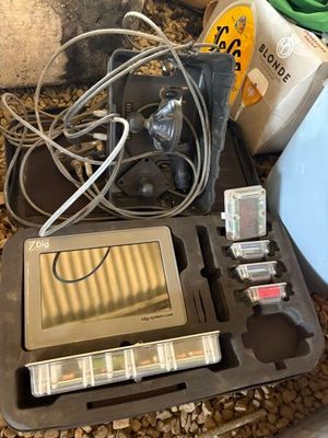 un ordinateur portable et d'autres appareils électroniques dans une mallette posée par terre