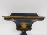 an antique black and gold shelf with a bird on it