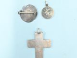 two silver crosses and a coin are on a blue surface