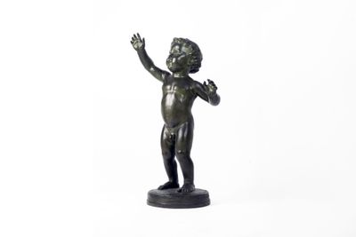 une petite statue en bronze représentant un garçon les mains en l'air