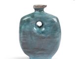 a blue vase with a hole in it on a white surface
