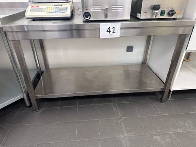 une table en acier inoxydable sur laquelle se trouvent un micro-ondes et un grille-pain