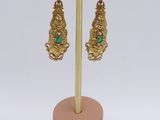 a pair of gold and emerald earrings on a stand