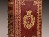 an old book with a red cover and gold decoration