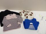 several baby clothes are laid out on a white table