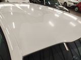 a white car parked in a showroom with other cars