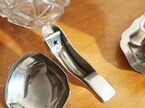 some silver spoons are sitting on a wooden table next to a teapot