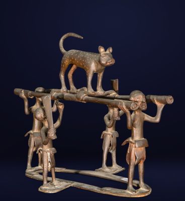 a bronze figurine of a cat on top of a group of people