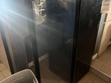 a black refrigerator and a trash can in a kitchen