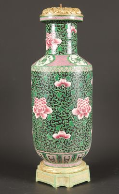 green and pink vase with flowers on a stand on a black background
