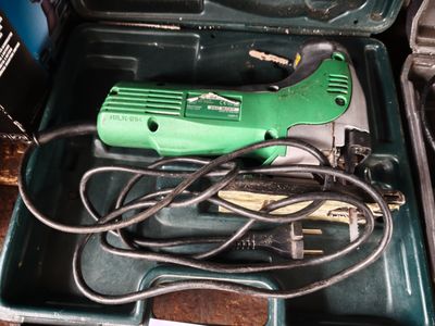 a green and black electric tool in a green case