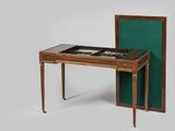 une petite table avec un plateau en verre et un napperon vert