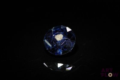 a close up of a blue and white stone on a black surface