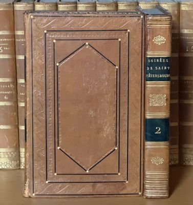 de nombreux livres sur une étagère, avec une horloge posée dessus