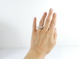 a woman ' s hand holding a ring on a white surface