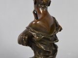 a bronze statue of a woman holding a flower on a marble base