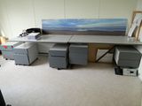 une photo d'un bureau dans une pièce où est accroché un tableau au mur