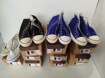Plusieurs paires de Converse bleues et blanches sont alignées sur des cartons