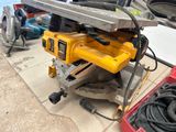 une scie circulaire jaune posée sur une table, à côté d'autres outils