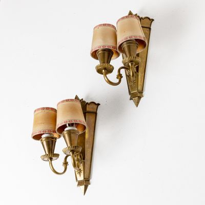 pair of brass wall sconces with pink shades on each of them