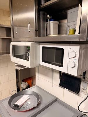 a pan on a stove in a kitchen with a microwave above it