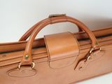 a brown leather bag with two handles on a white surface