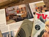 magazines and magazines on a table with a woman in the background