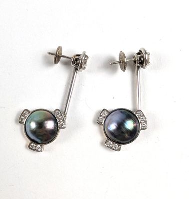 une paire de boucles d'oreilles en perles noires et diamants sur fond blanc