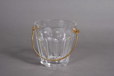 a glass vase with a gold handle on a gray surface