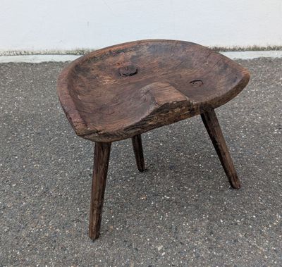 a small wooden stool sitting on top of the pavement
