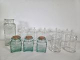 many glass jars and jars with cork lids on a table