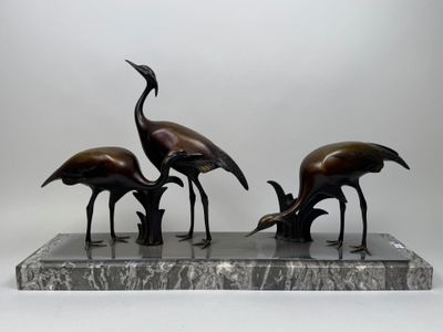 trois statues d'oiseaux en bronze posées sur un socle en marbre