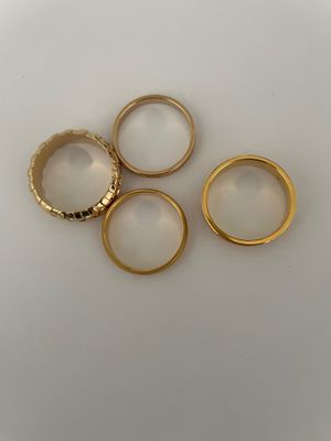 four gold wedding rings on a white surface
