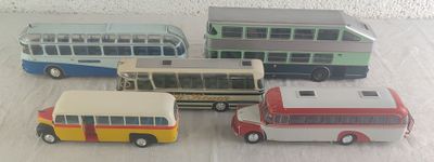 quatre petits bus en jouet rangés les uns à côté des autres