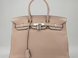un sac à main en cuir beige muni d'un fermoir métallique sur la poignée
