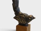 statue of a bird on a wooden base on a white background