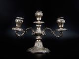 un chandelier plaqué argent avec trois bougies sur fond noir