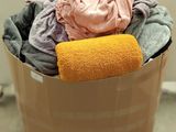 a bucket full of clothes and a towel on the floor